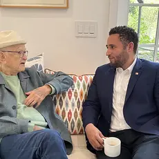 Norman Lear and Svante Myrick sit next to each other on a sofa discussing antisemitism.
