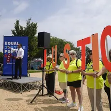 Svante Myrick speaks at a podium while activists hold signs spelling JUSTICE