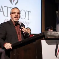 Rick Green standing at a podium and holding a microphone.